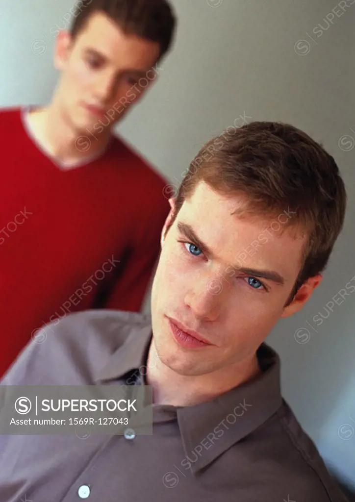 Two men, one looking into camera