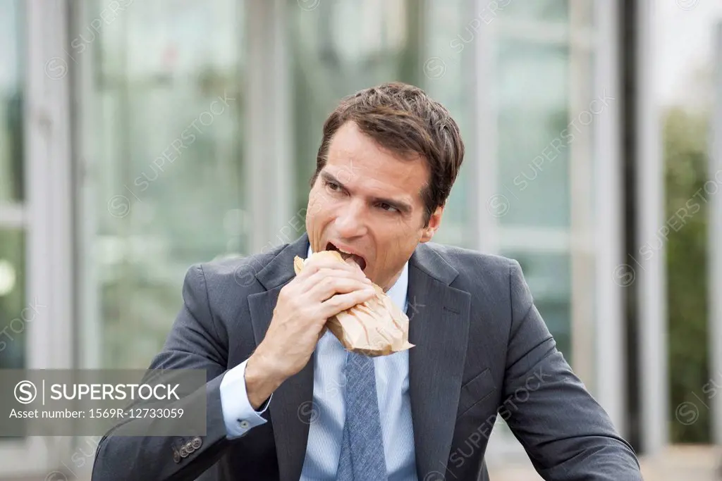 Businessman eating sandwich outdoors