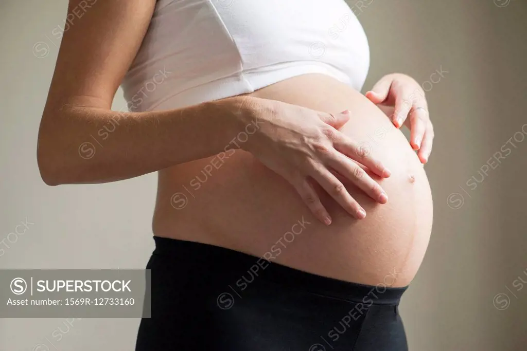 Pregnant woman massaging swollen abdomen