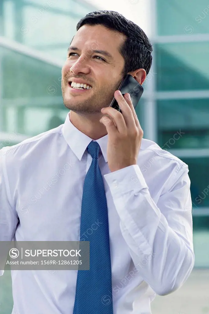 Businessman using cell phone, smiling