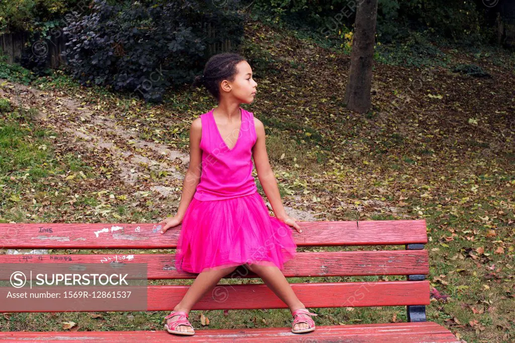 Girl sitting alone on park bench, looking away in thought