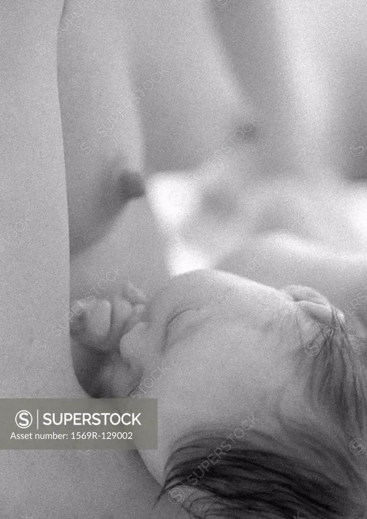 Infant lying in mother´s arms near bare breasts, b&w