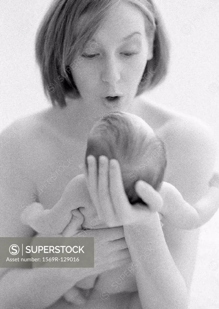 Mother holding infant in hands, making faces, b&w