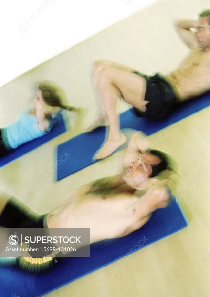 People doing sit-ups on mats, blurred