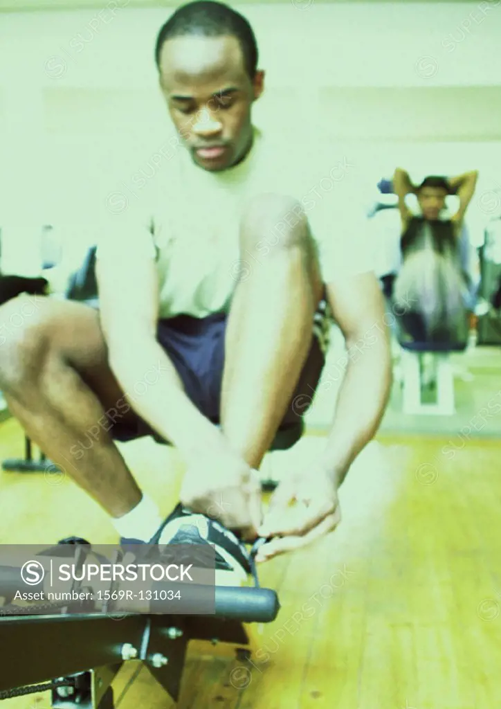 Man tying shoe laces in gym