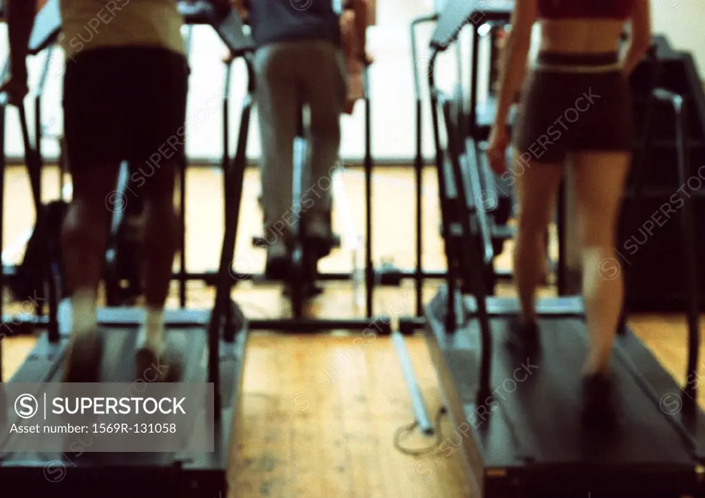 People using exercise equipment in gym, lower section