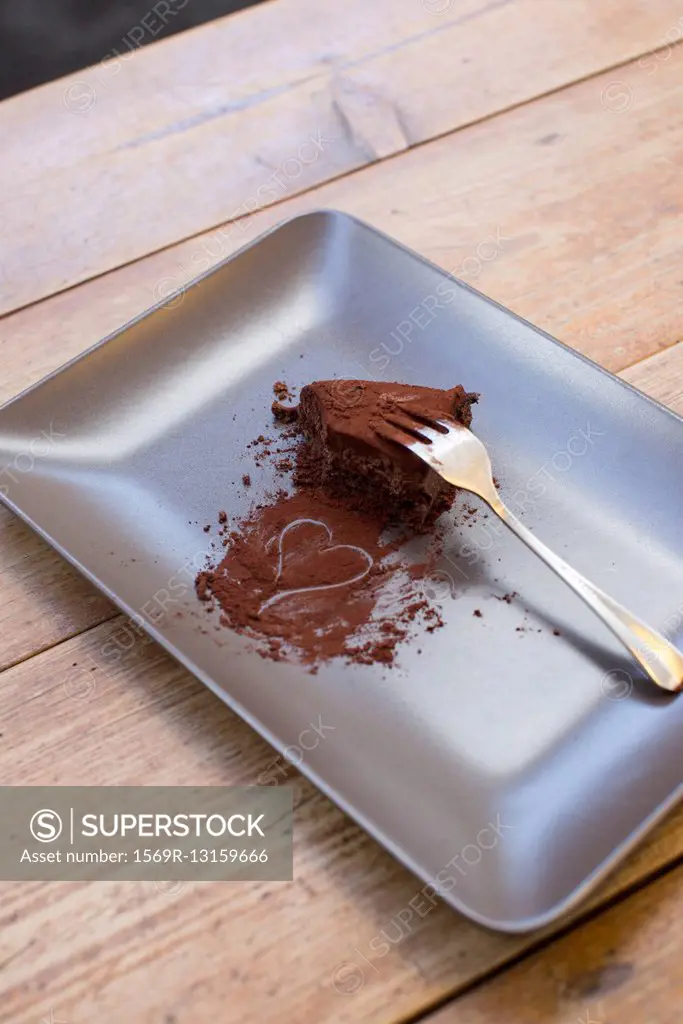 Heart drawn in cocoa powder and half eaten chocolate cake