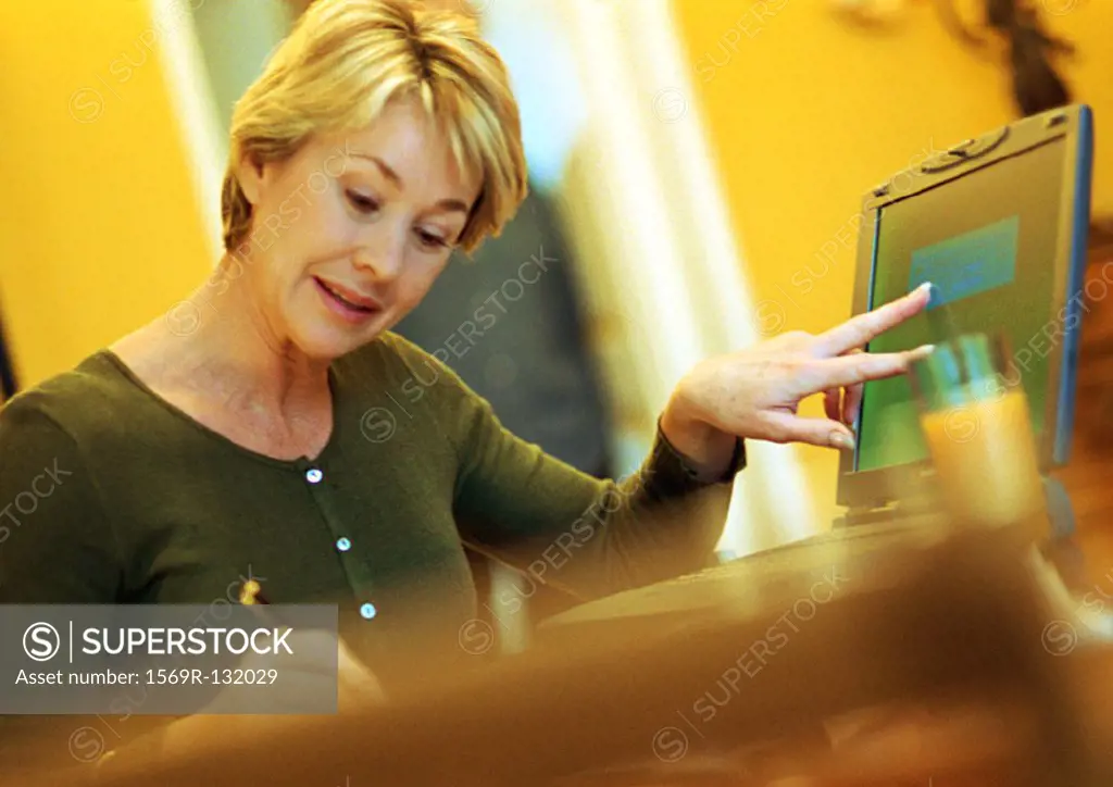 Mature woman using laptop, taking notes