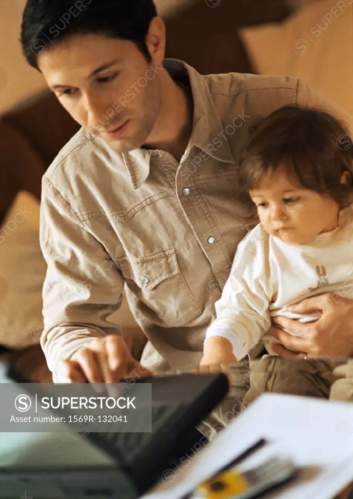 Father and baby, father using laptop, baby sitting on father´s lap