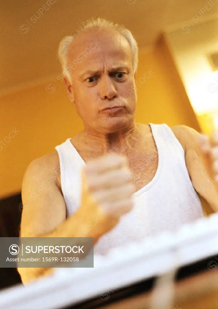Mature man making fist, looking unhappy, with computer keyboard