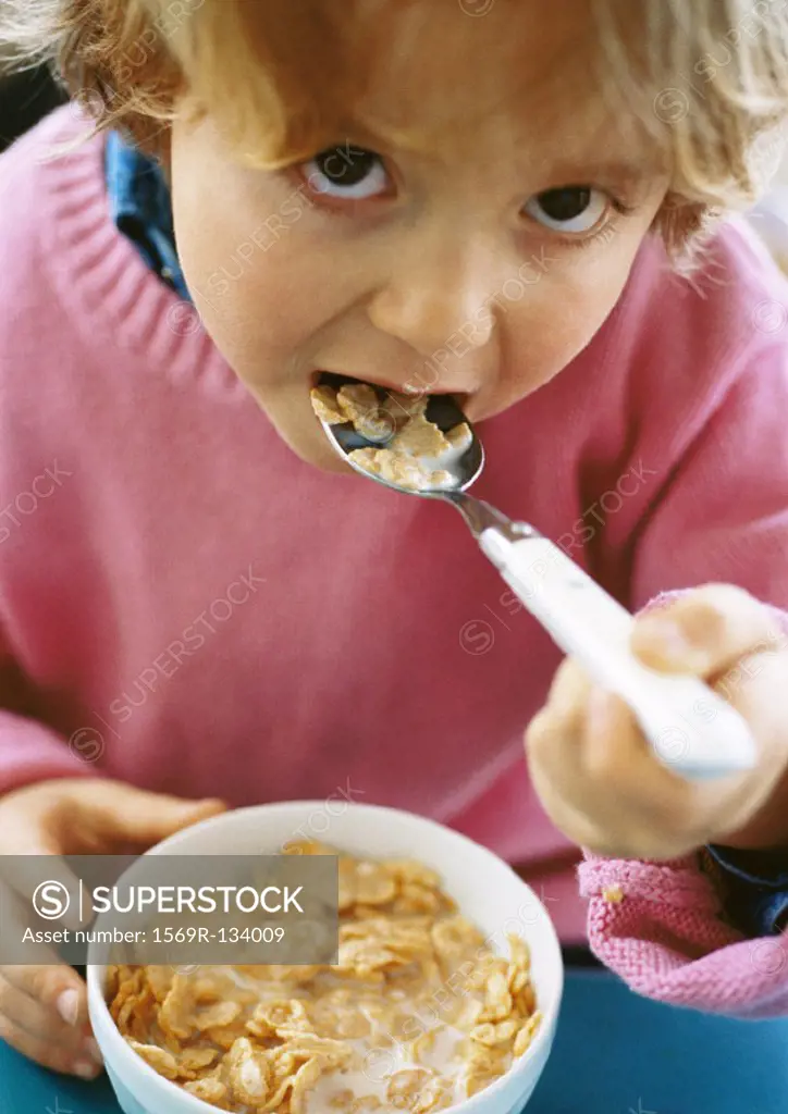 Little girl eating cereal, looking into camera, portrait