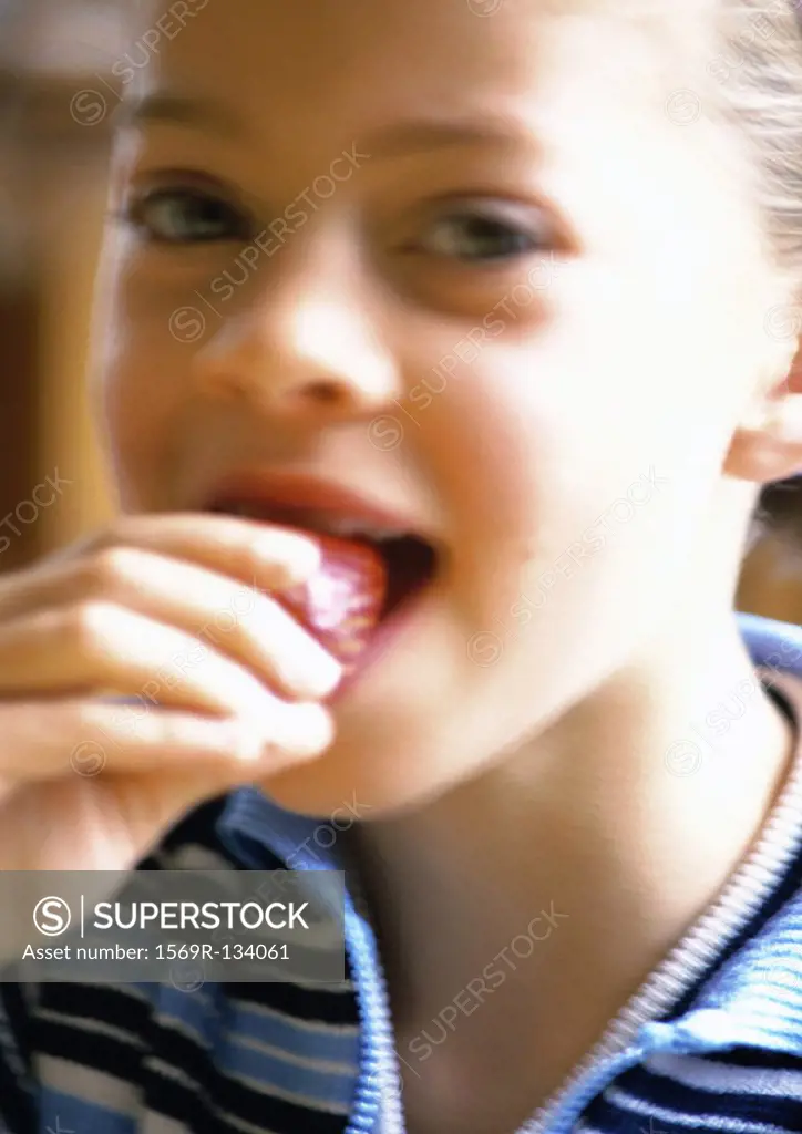 Young girl eating strawberry, portrait