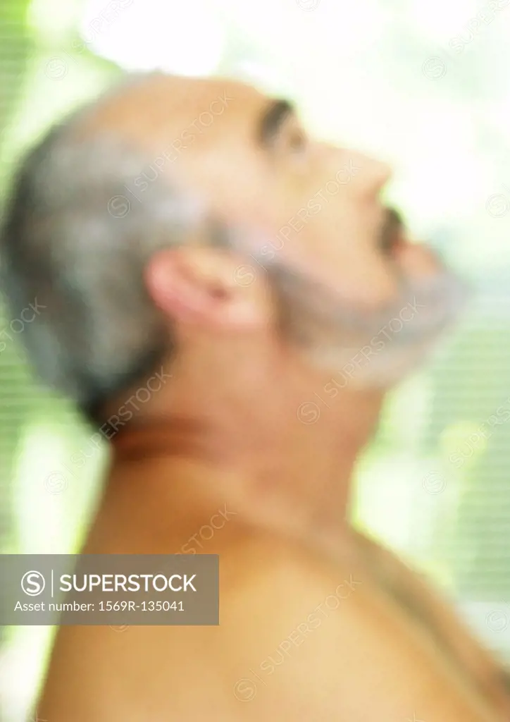 Mature man looking up, side view, blurred