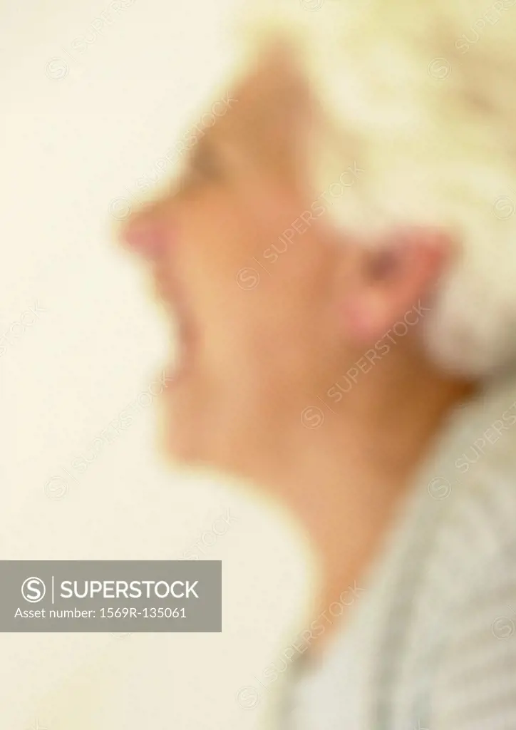 Senior woman screaming, side view, close-up, portrait, blurred
