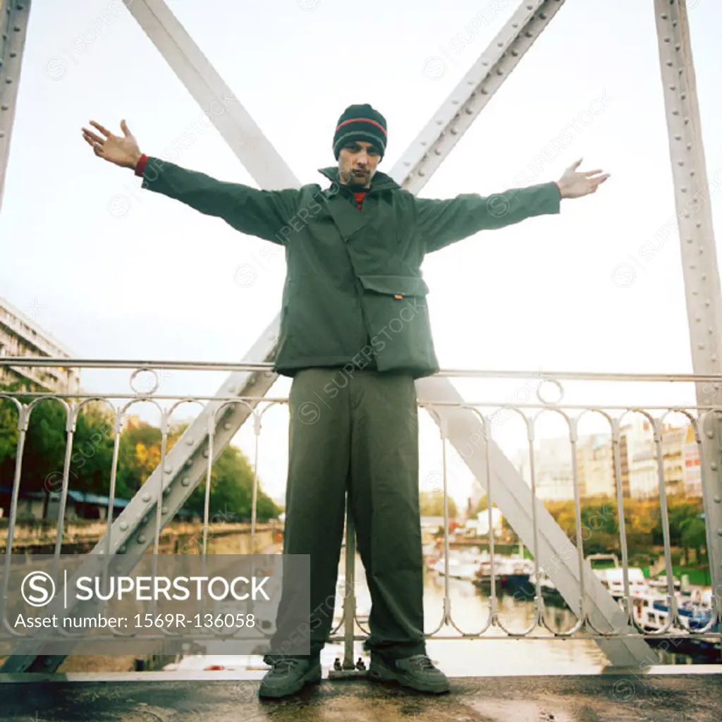 Man standing on bridge with arms stretched out