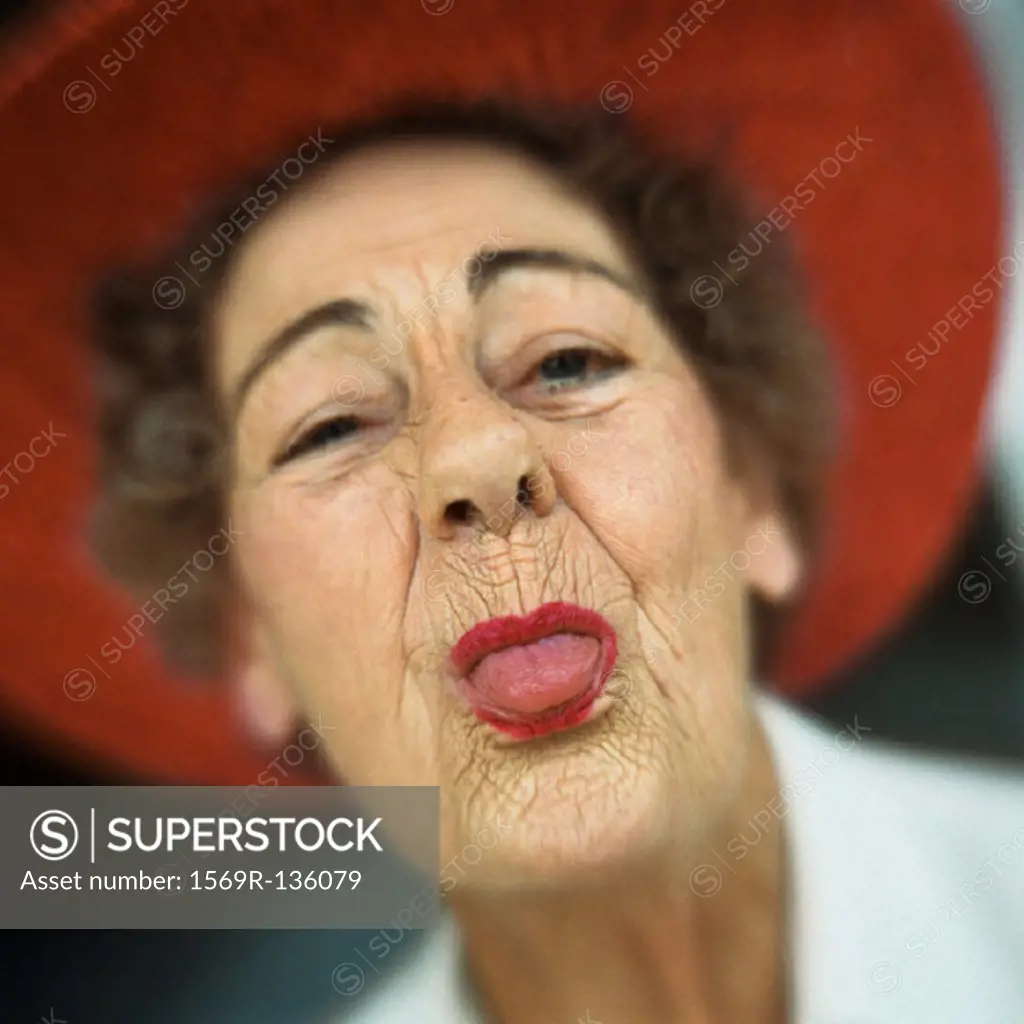 Portrait of senior woman wearing red hat with tongue sticking out