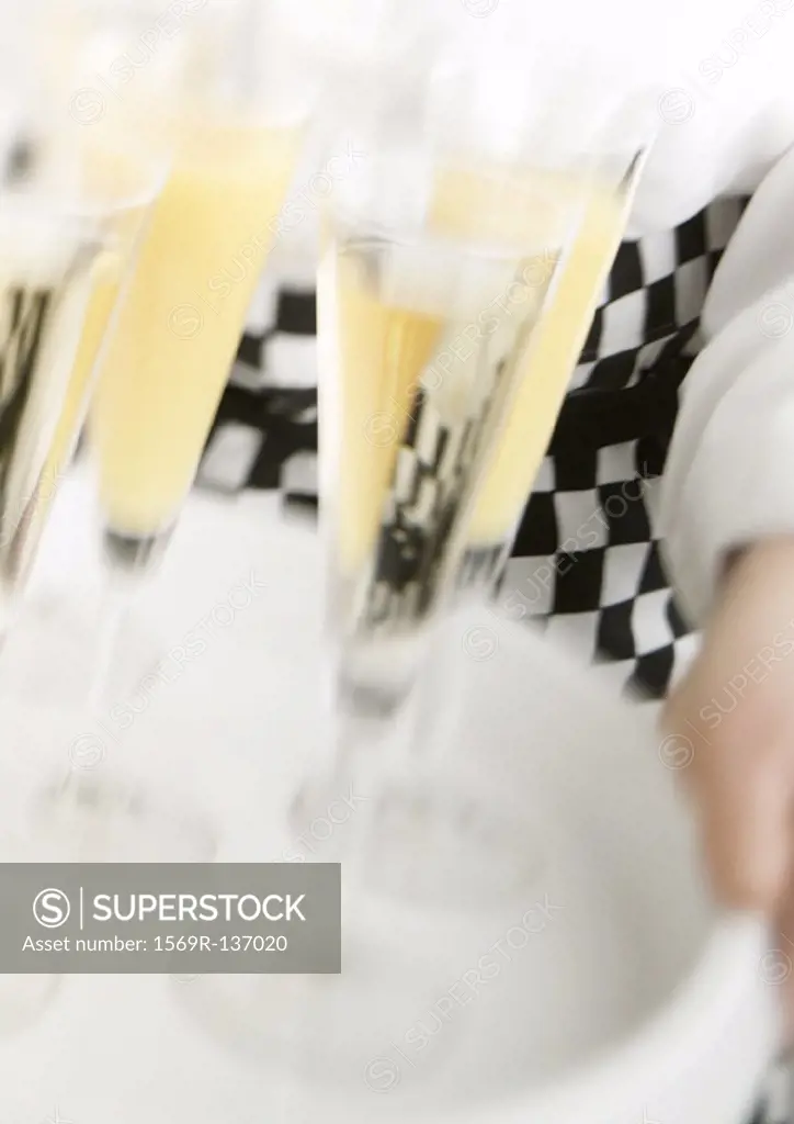 Waiter carrying tray of Champagne, blurred motion, close-up