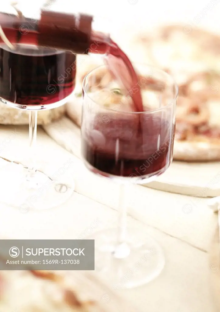 Two glasses of red wine being poured