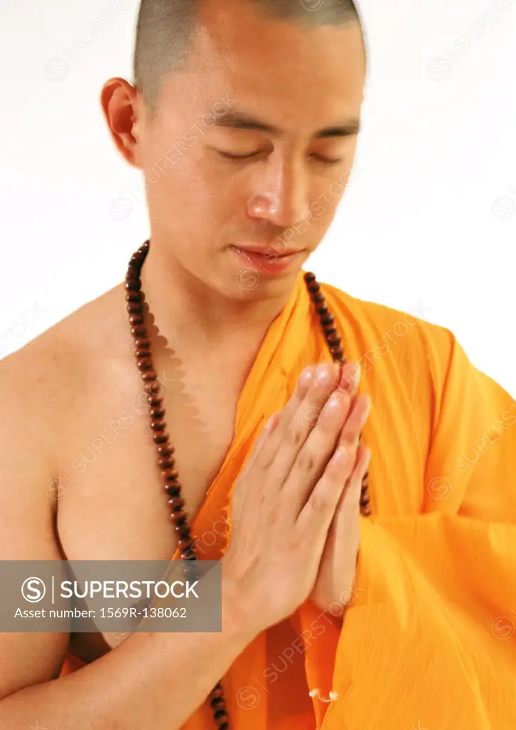 Buddhist monk meditating with hands together