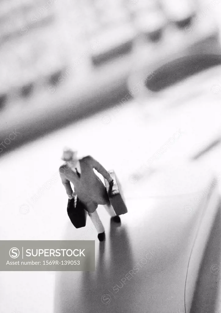 Small toy figure standing on computer mouse, b&w