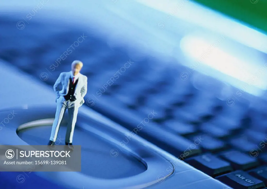 Small toy figure on computer keyboard, focus on figure, close-up