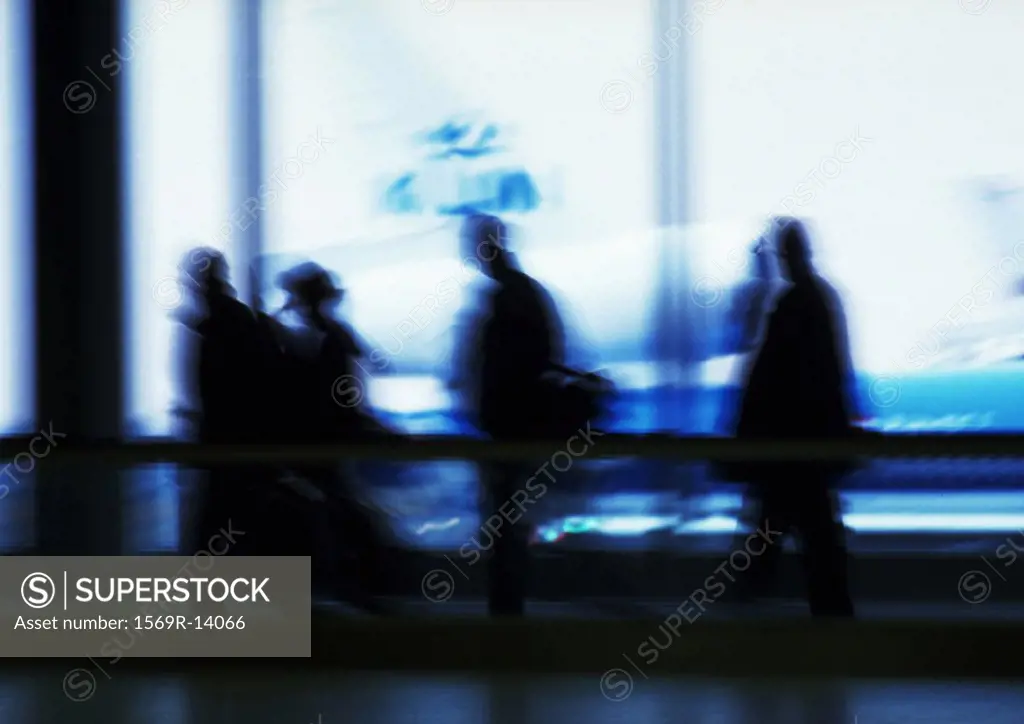 Silhouette of people in airport in front of windows, blurred