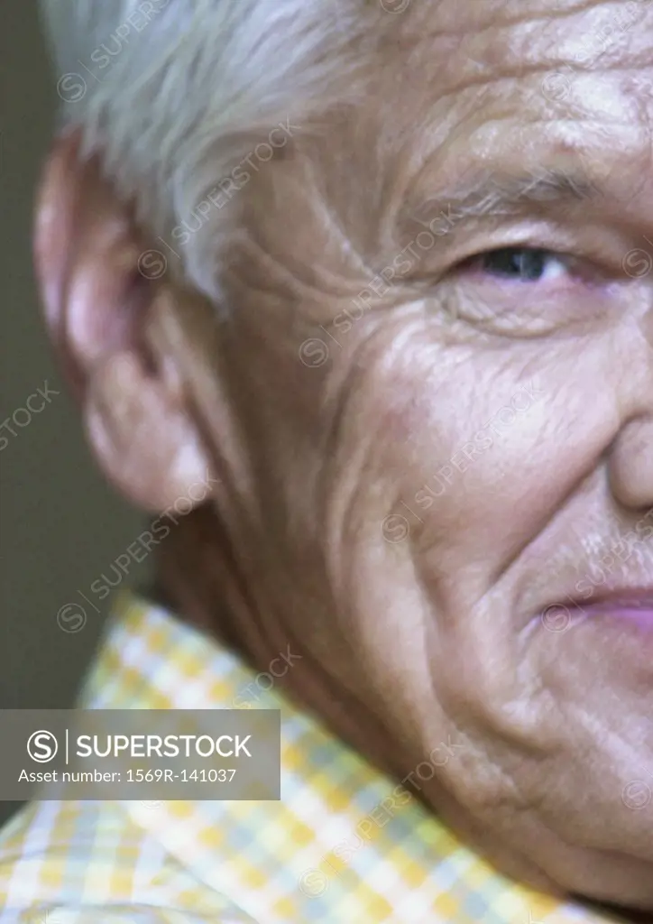 Senior man looking into camera, partial view, close-up