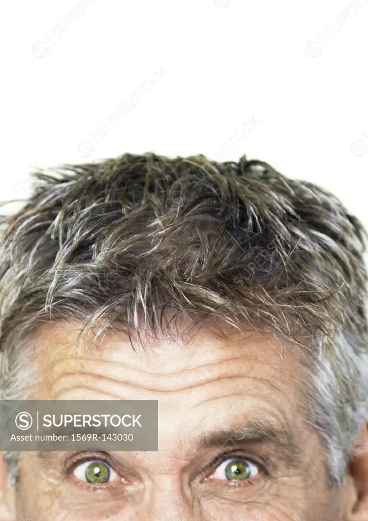 Mature man raising eyebrows and looking at camera, partial view, close-up