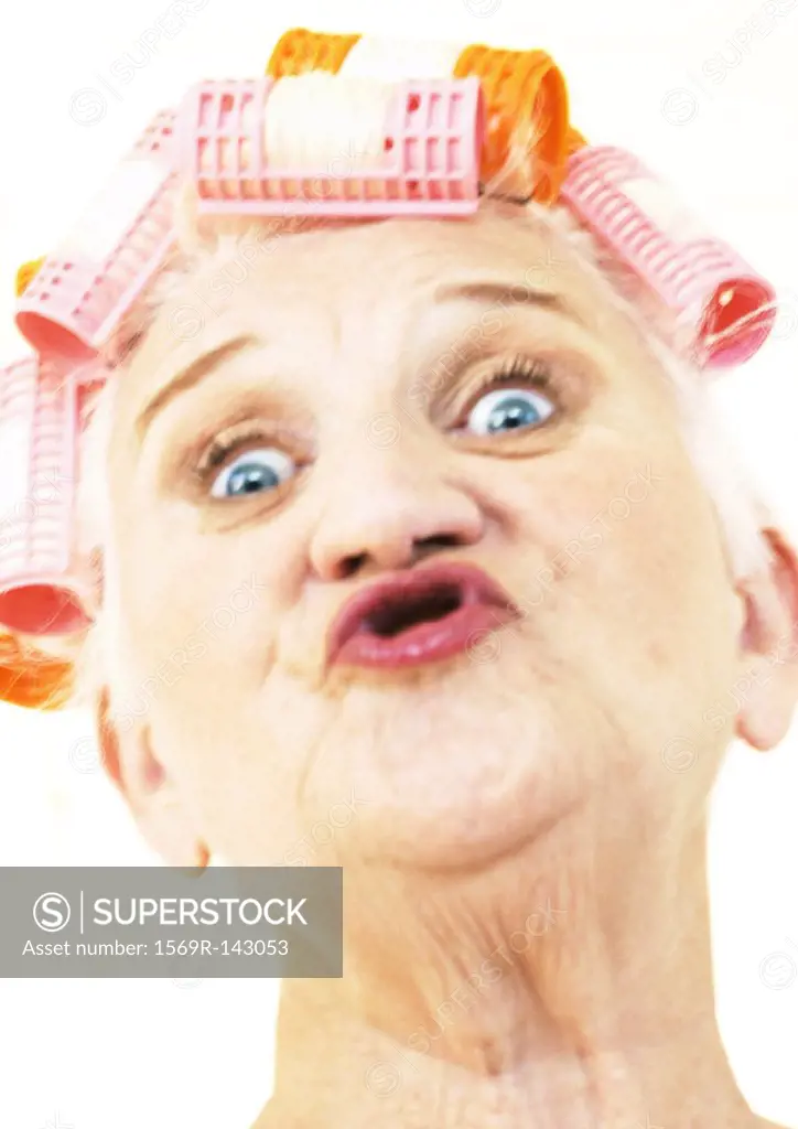 Elderly woman puckering lips and wearing hair rollers, portrait, close-up