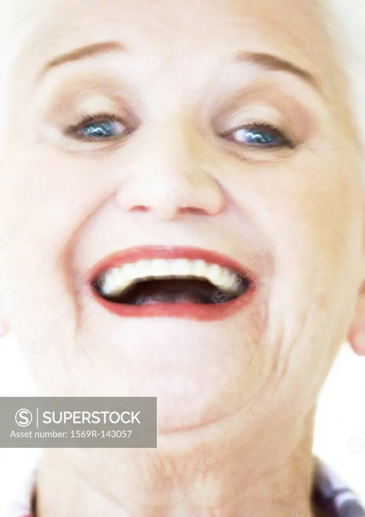 Senior woman smiling at camera, portrait, close-up, blurred