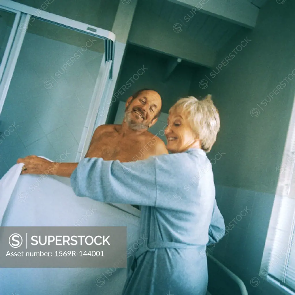 Mature woman holding towel in front of nude man