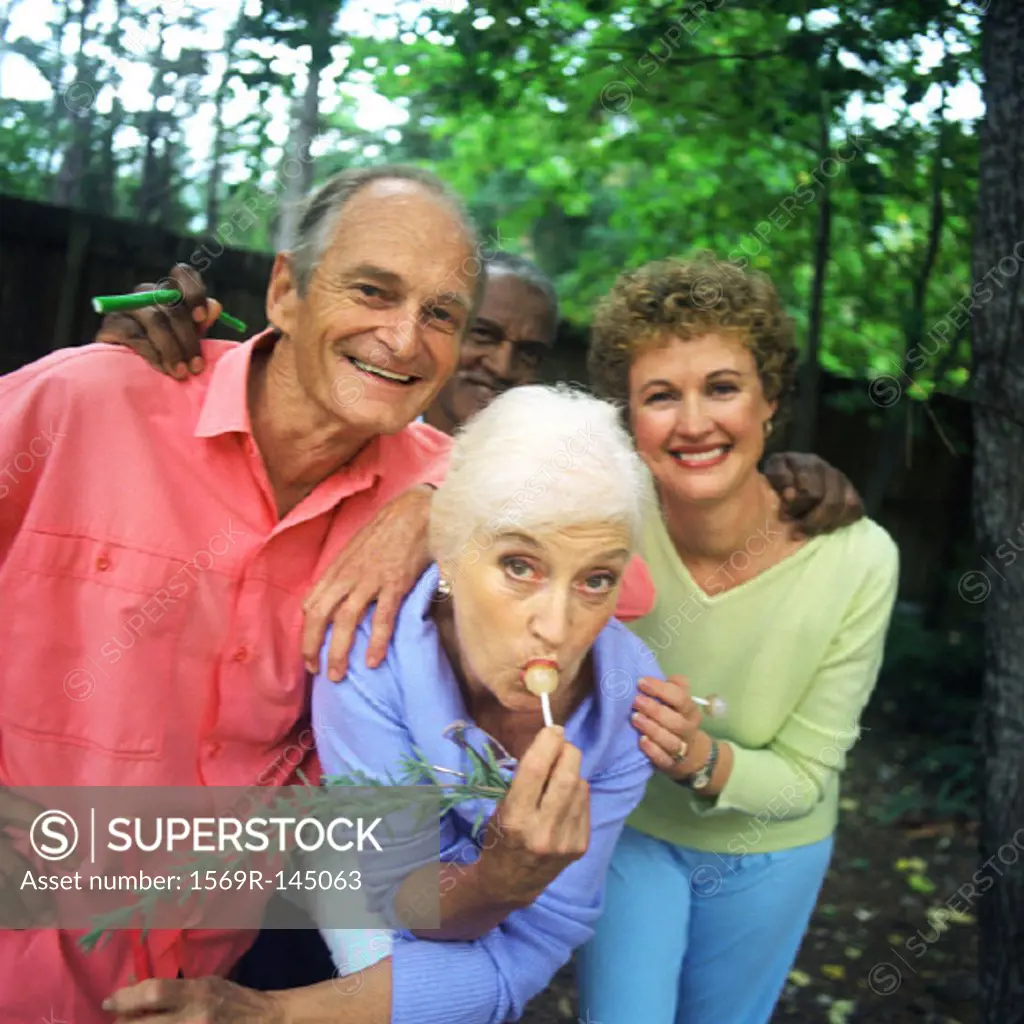 Four people standing outdoors, woman sucking lollipop