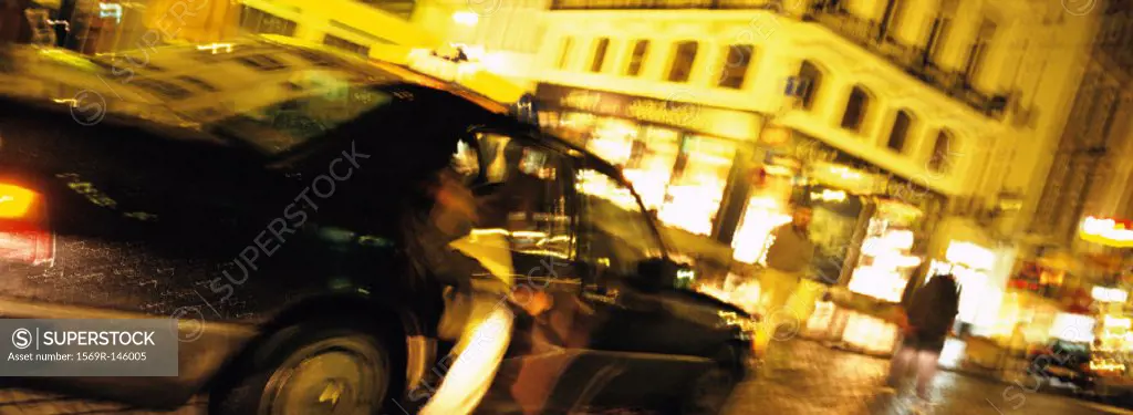 Person getting out of taxi at night, blurred