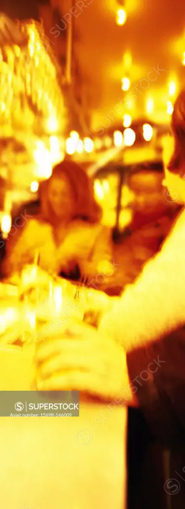 Adults drinking at bar, blurred