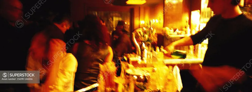 Bartender serving people at bar, blurred