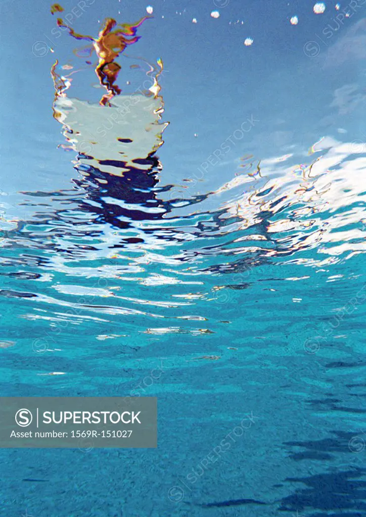 Person standing on diving board about to dive, underwater view