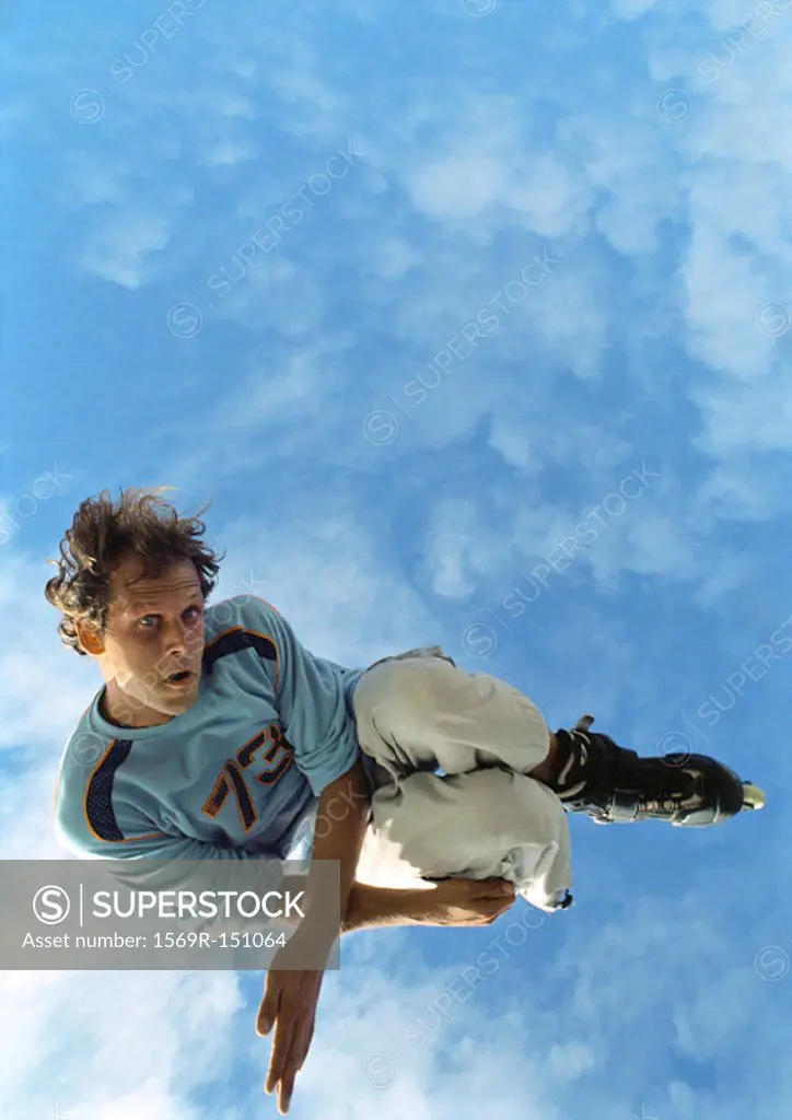 Young man on rollerblades, jumping, mid-air, low angle