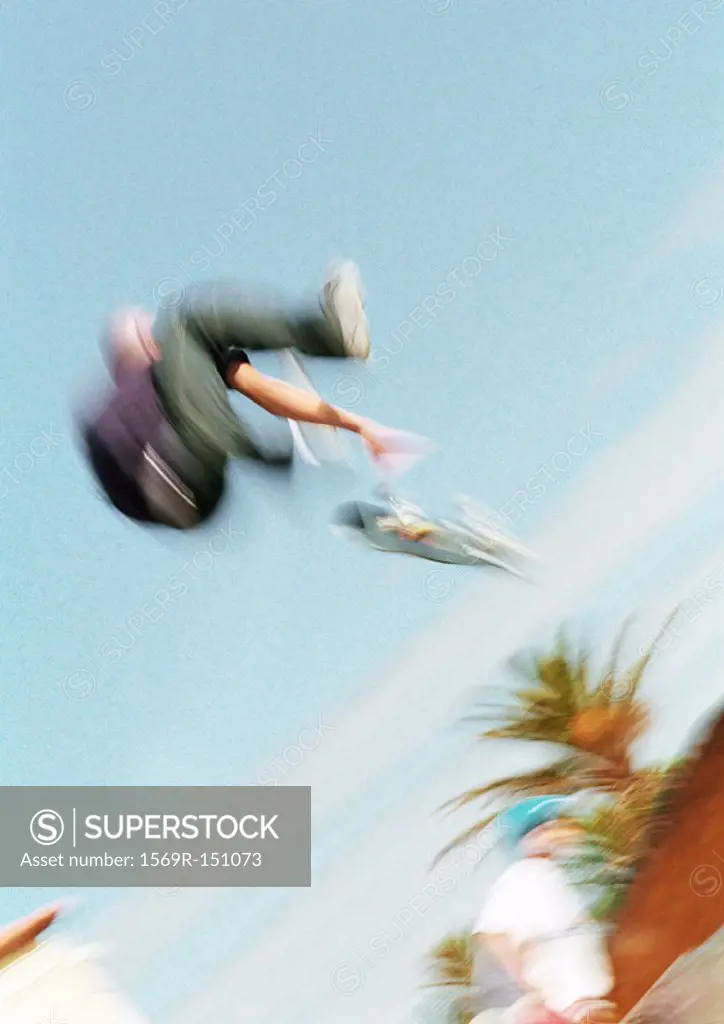 Young man on skateboard, jumping, mid-air, blurred, low angle view