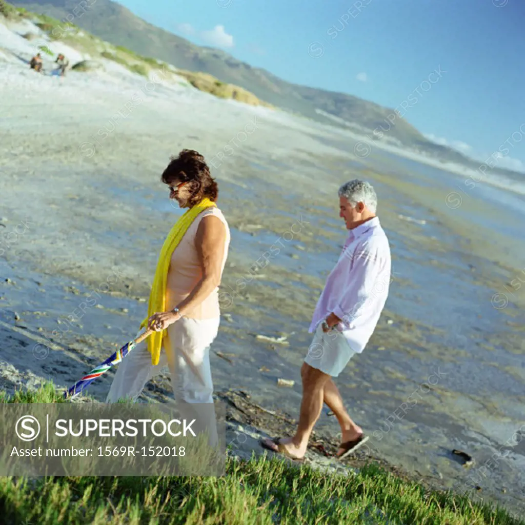 Mature couple walking on beach, side view