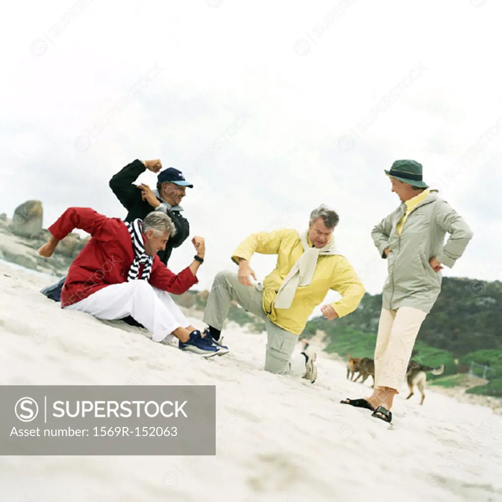 Mature group pretending to flex muscles on beach