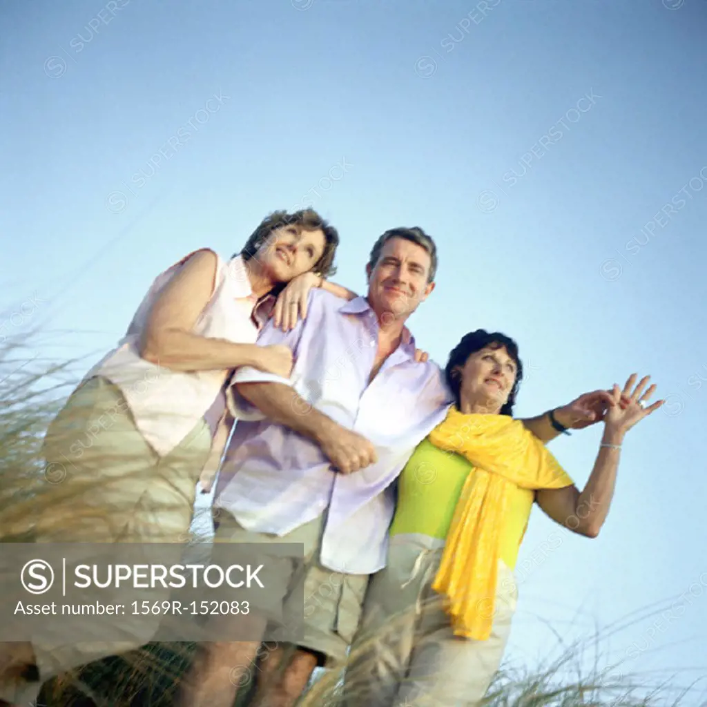 Mature friends standing in tall grass, low angle view, portrait