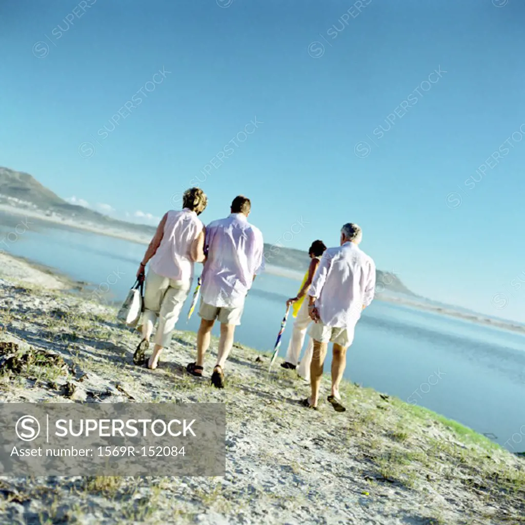 Two mature couples walking by the sea, rear view
