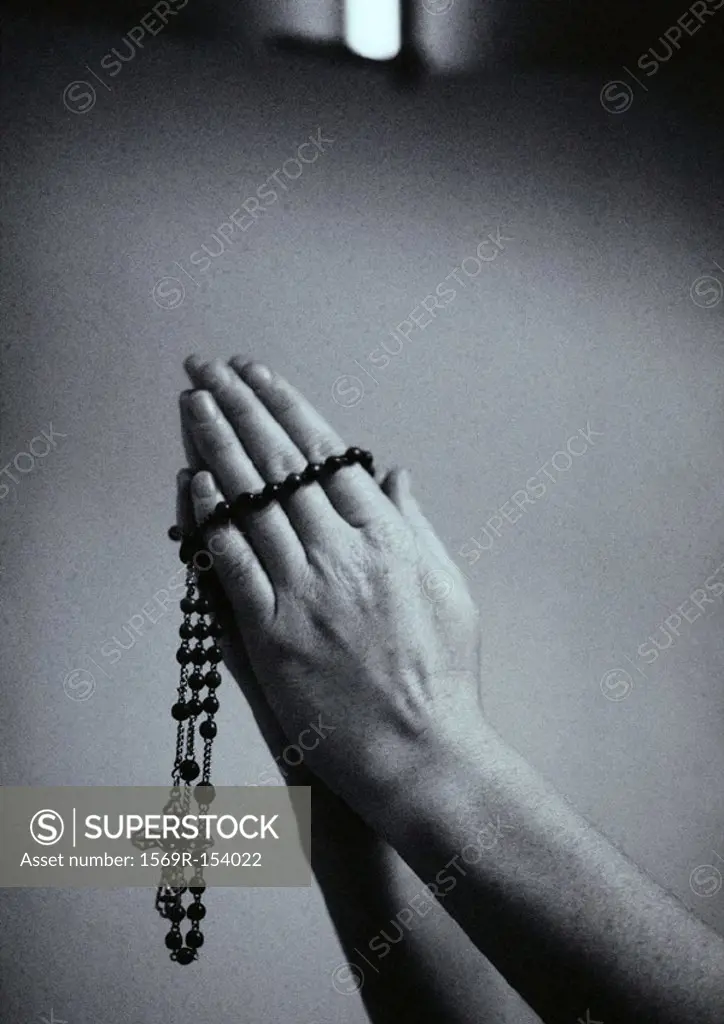 Hands holding rosary beads, b&w