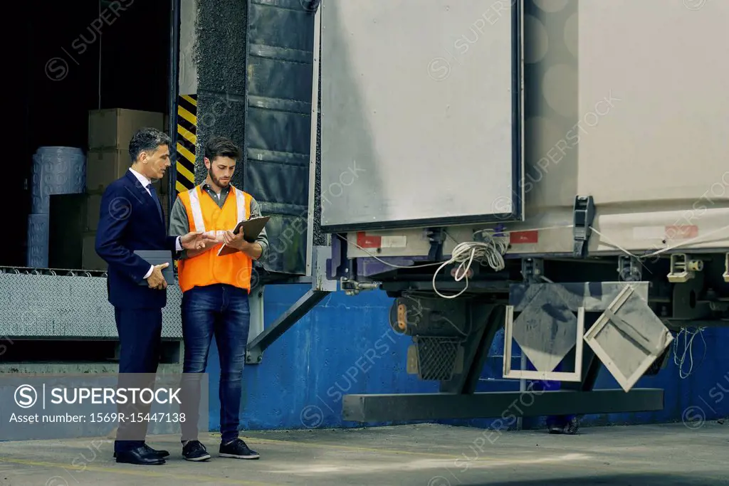 Worker and businessman discussing near lorry
