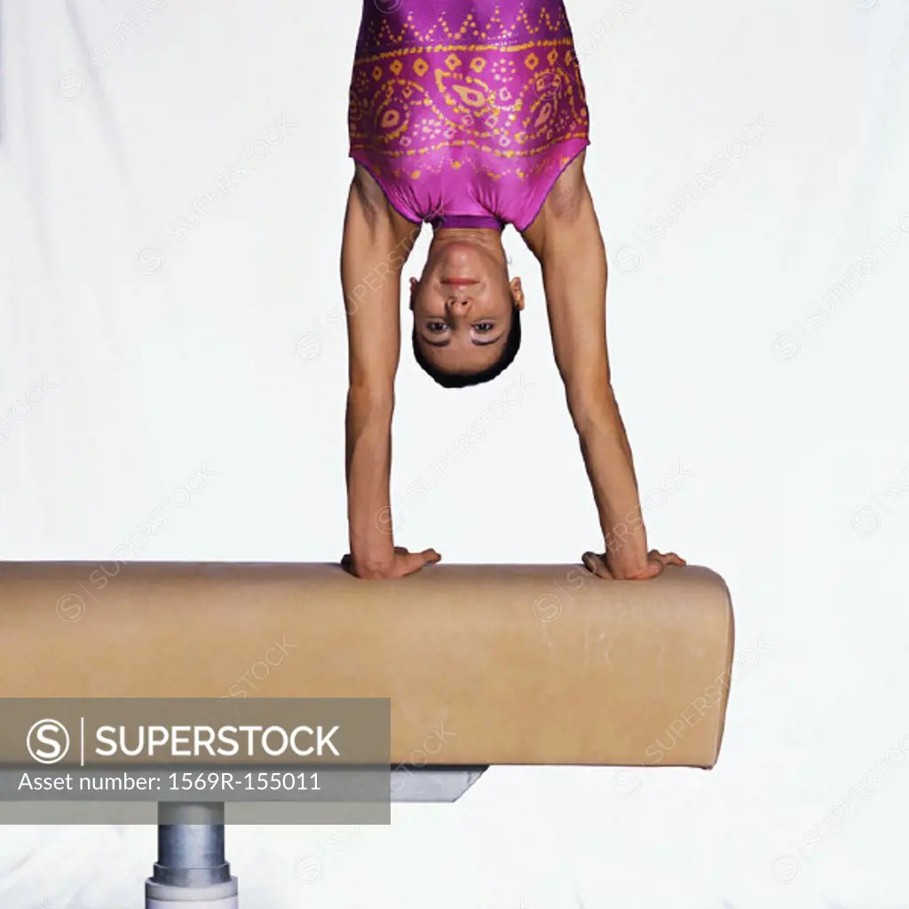 Female gymnast on pommel horse, upside down, upper section