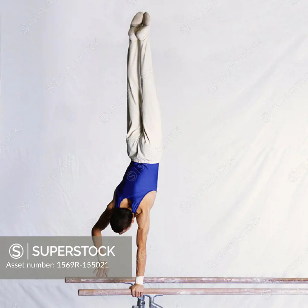 Male gymnast performing routine on parallel bars