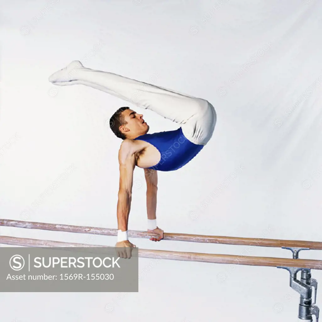 Young male gymnast on parallel bars, side view