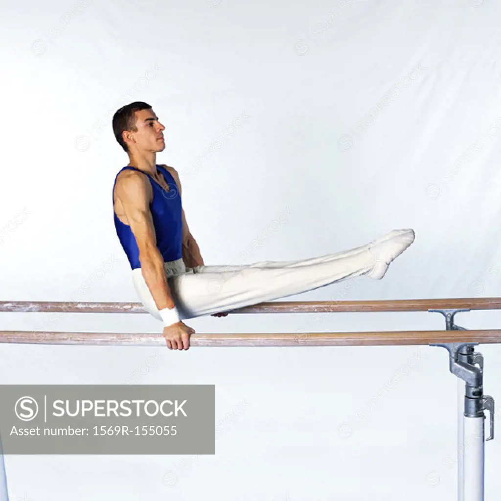 Young male gymnast on parallel bars, side view