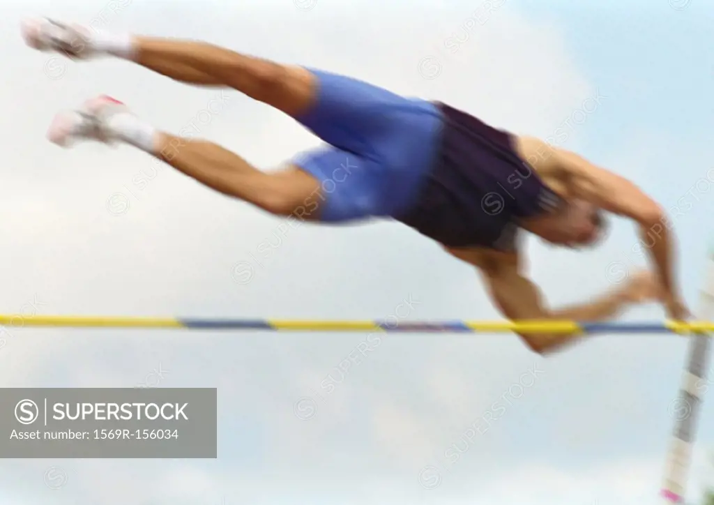 Male pole vaulter in mid-air, low angle view, blurred motion
