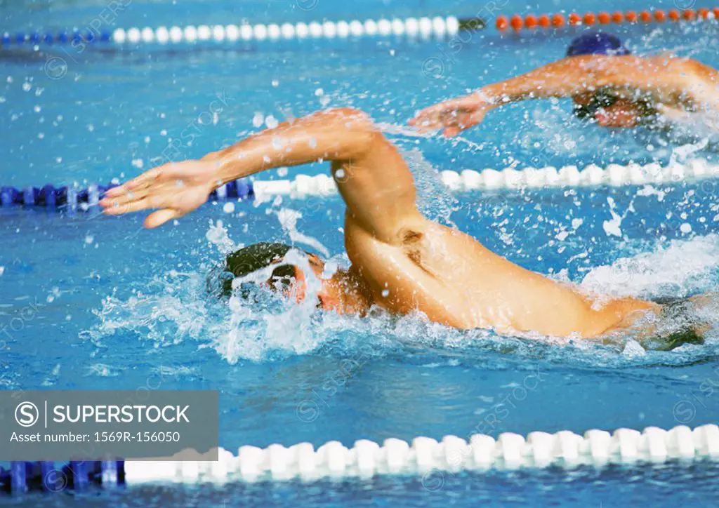 Male swimmers doing freestyle in pool, close-up